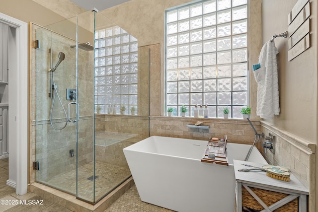 full bathroom featuring a freestanding bath, wainscoting, a shower stall, and tile walls