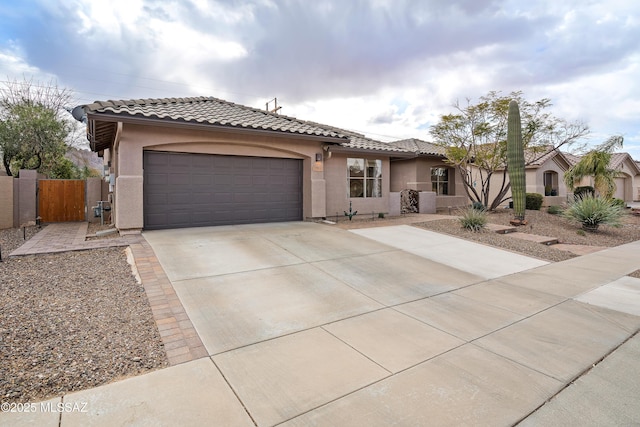 mediterranean / spanish-style home featuring concrete driveway, an attached garage, a tile roof, and stucco siding