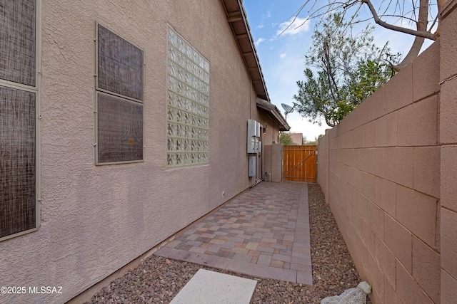 view of home's exterior featuring a gate, a patio area, fence, and stucco siding