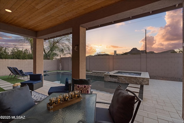 patio terrace at dusk with a fenced backyard and a fenced in pool