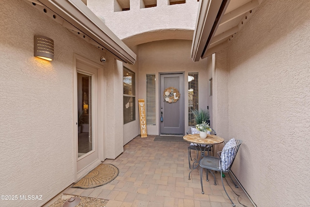 view of exterior entry featuring a patio and stucco siding