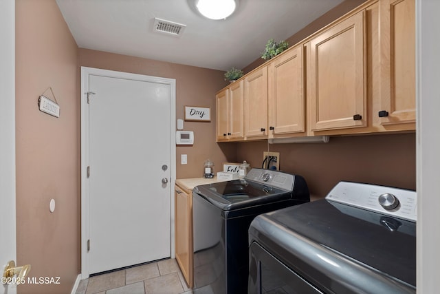 laundry room with light tile patterned floors, washer and clothes dryer, cabinet space, and visible vents