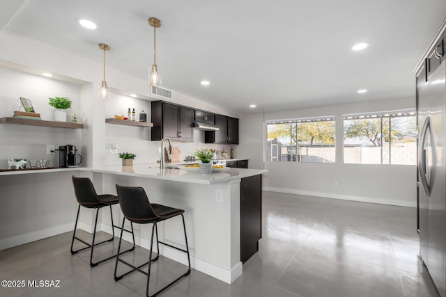 kitchen with visible vents, light countertops, open shelves, stainless steel fridge, and a kitchen bar