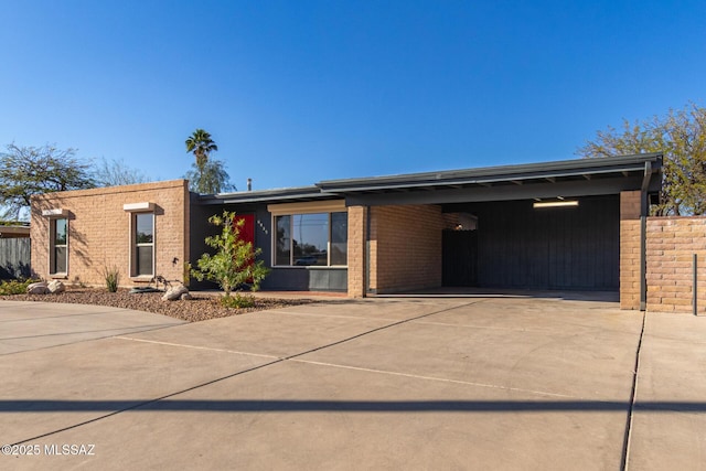 mid-century modern home with concrete driveway, brick siding, and fence