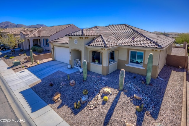 mediterranean / spanish house with concrete driveway, an attached garage, a tile roof, and stucco siding