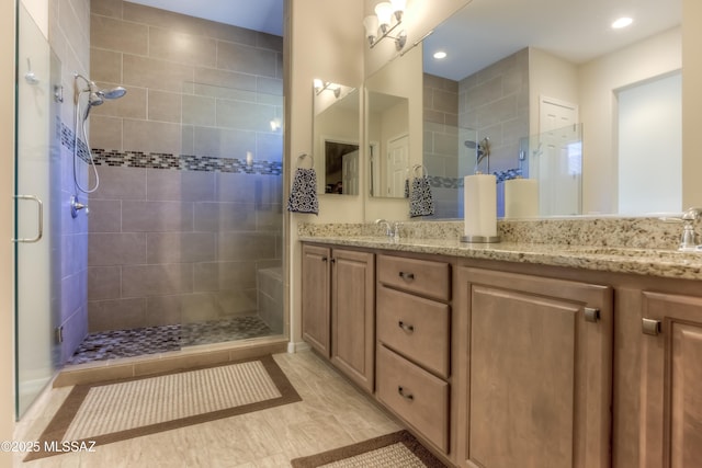 full bathroom with double vanity, a stall shower, and a sink