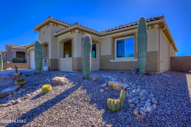 mediterranean / spanish-style house featuring a tiled roof, an attached garage, and stucco siding