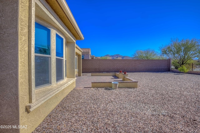 view of yard featuring a patio area, a fenced backyard, and a mountain view