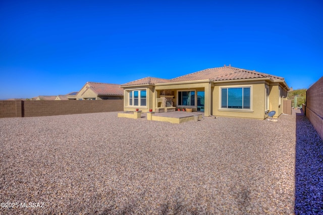 rear view of house with stucco siding, a fenced backyard, a patio, and a tiled roof