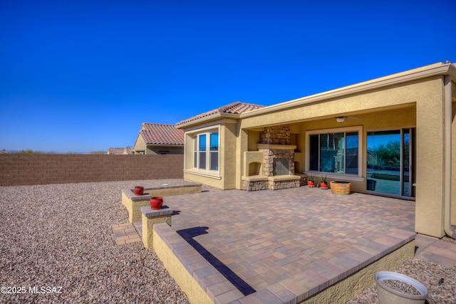 view of patio with a ceiling fan, a fireplace, and fence