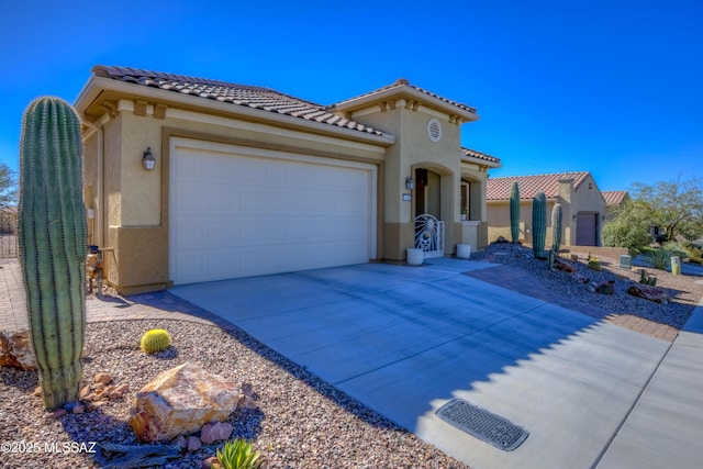 mediterranean / spanish-style house with driveway, a tiled roof, an attached garage, and stucco siding