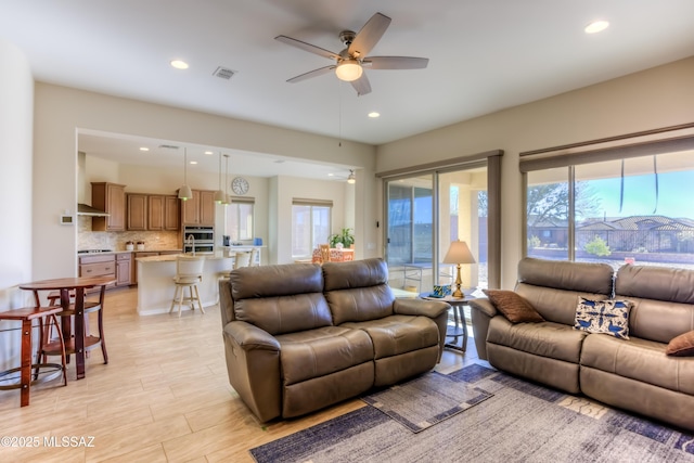 living room with a ceiling fan, recessed lighting, visible vents, and light wood finished floors