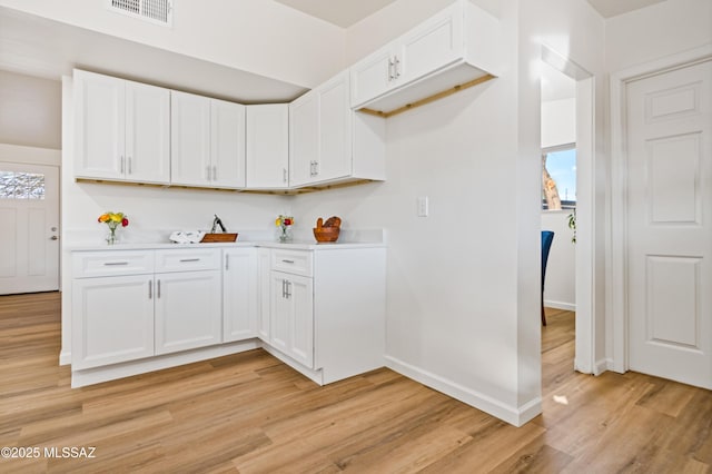 kitchen featuring light wood finished floors, visible vents, white cabinetry, and light countertops