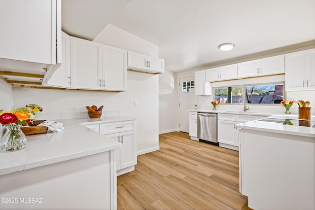 kitchen with light wood finished floors, baseboards, stainless steel dishwasher, white cabinetry, and a sink