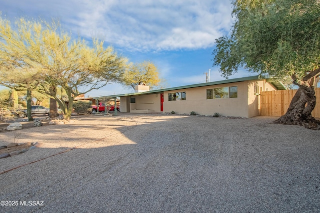 ranch-style home featuring a patio, stucco siding, fence, an attached carport, and driveway