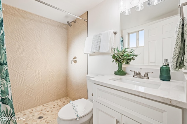 bathroom featuring tiled shower, vanity, and toilet