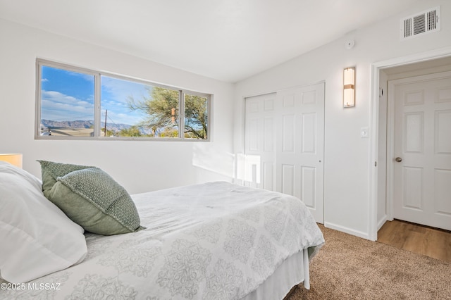 carpeted bedroom featuring vaulted ceiling, a closet, visible vents, and baseboards