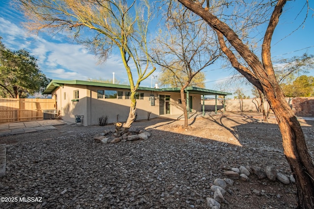 rear view of house featuring central AC unit, stucco siding, fence, and a patio