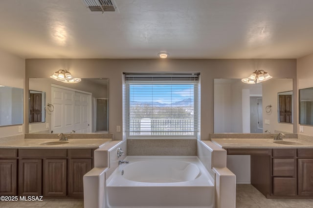 bathroom featuring visible vents, a sink, a garden tub, and tile patterned floors