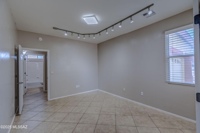 spare room featuring rail lighting, light tile patterned flooring, visible vents, and baseboards