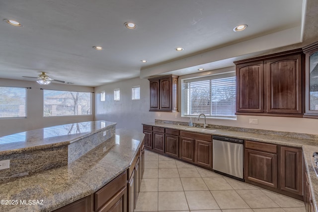 kitchen featuring recessed lighting, light stone counters, stainless steel dishwasher, a sink, and light tile patterned flooring