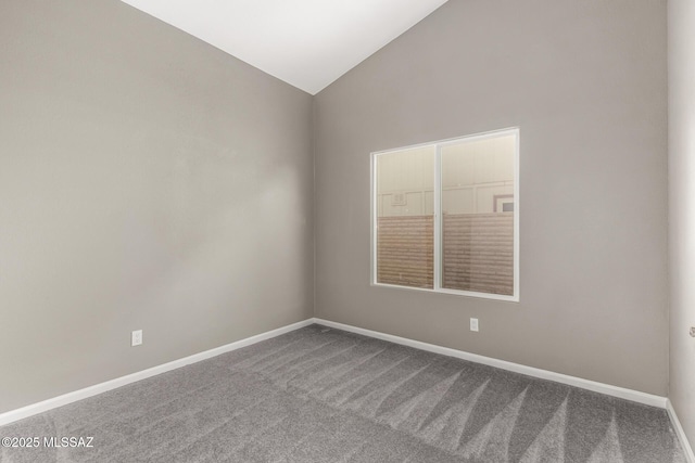 carpeted spare room with baseboards and lofted ceiling