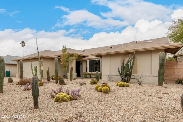 view of front of property with a garage, fence, and stucco siding