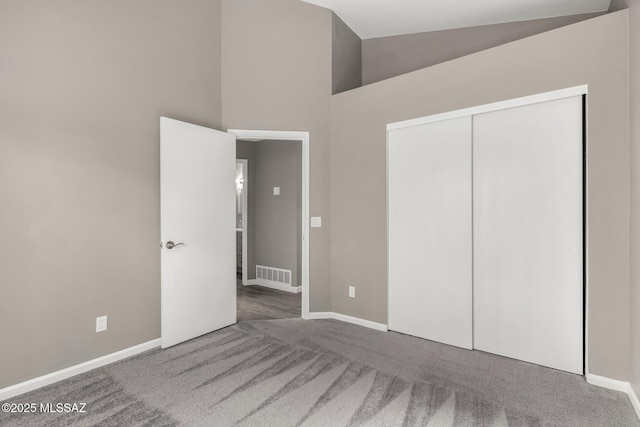 unfurnished bedroom featuring baseboards, visible vents, high vaulted ceiling, a closet, and carpet flooring