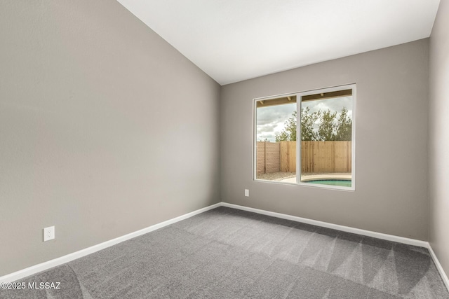 unfurnished room featuring vaulted ceiling, baseboards, and carpet floors