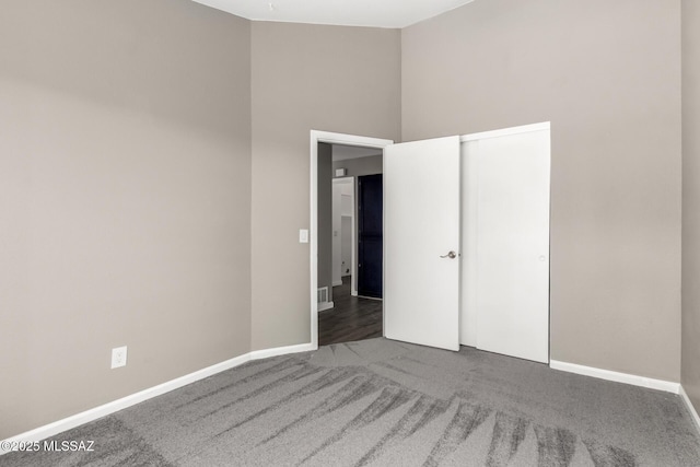 unfurnished bedroom with carpet, baseboards, and a towering ceiling