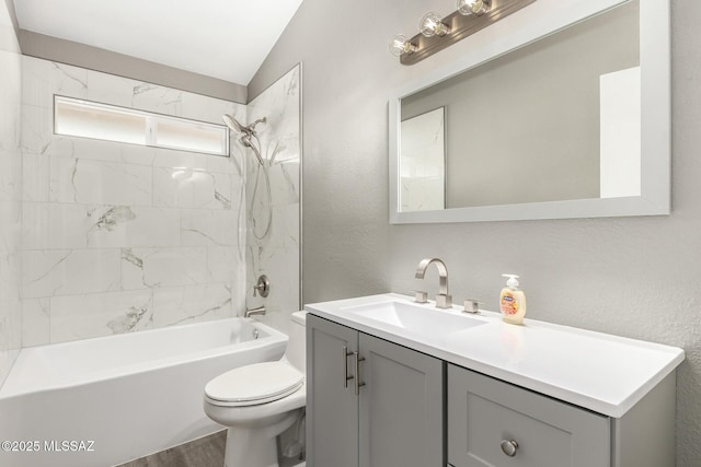 bathroom with toilet, vaulted ceiling, a textured wall, vanity, and  shower combination