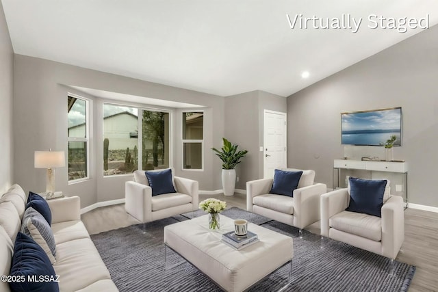 living room featuring baseboards, wood finished floors, and vaulted ceiling