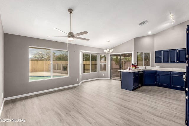 kitchen featuring visible vents, a peninsula, blue cabinetry, light countertops, and vaulted ceiling