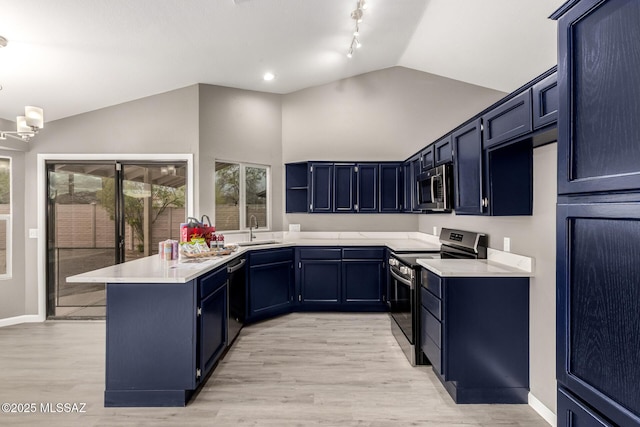 kitchen featuring a sink, appliances with stainless steel finishes, a peninsula, light countertops, and lofted ceiling