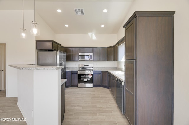 kitchen featuring hanging light fixtures, appliances with stainless steel finishes, sink, and dark brown cabinets