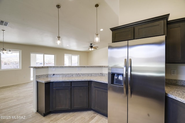 kitchen with a healthy amount of sunlight, light stone countertops, and stainless steel refrigerator with ice dispenser