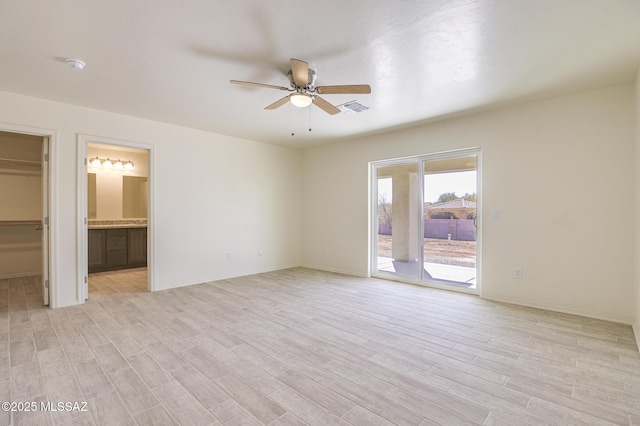 unfurnished bedroom featuring ceiling fan, light wood-type flooring, ensuite bath, and access to exterior