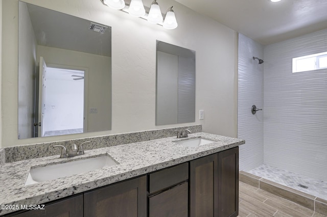 bathroom featuring vanity, wood-type flooring, and tiled shower