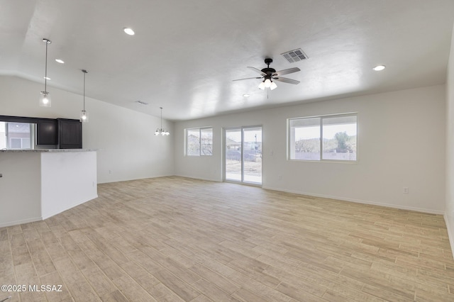 unfurnished living room with ceiling fan with notable chandelier, lofted ceiling, and light hardwood / wood-style flooring