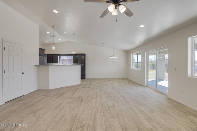 unfurnished living room featuring ceiling fan with notable chandelier, light hardwood / wood-style flooring, and lofted ceiling