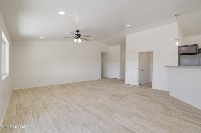 unfurnished living room featuring ceiling fan, light hardwood / wood-style flooring, and lofted ceiling