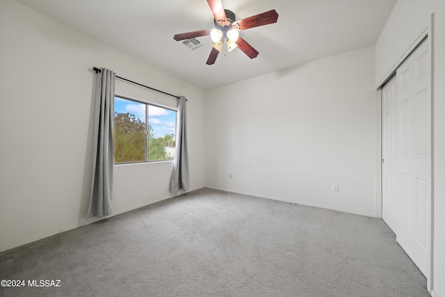 unfurnished bedroom featuring light carpet, a closet, and ceiling fan