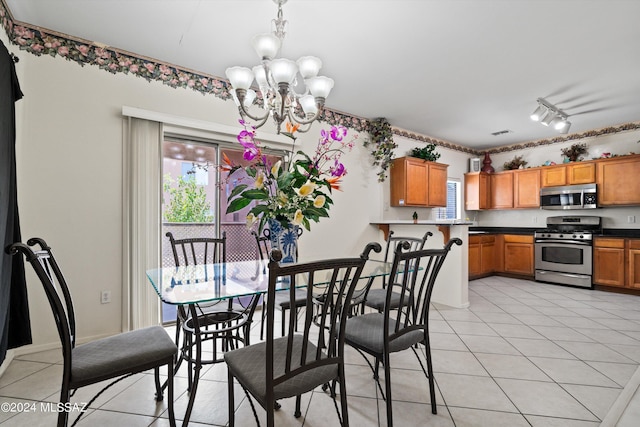 tiled dining area featuring track lighting and a chandelier