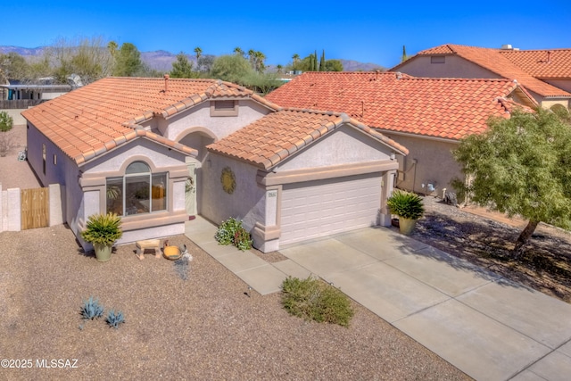 mediterranean / spanish-style house with concrete driveway, a tiled roof, an attached garage, and stucco siding