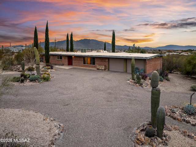 view of front of home featuring a garage, driveway, brick siding, and a mountain view