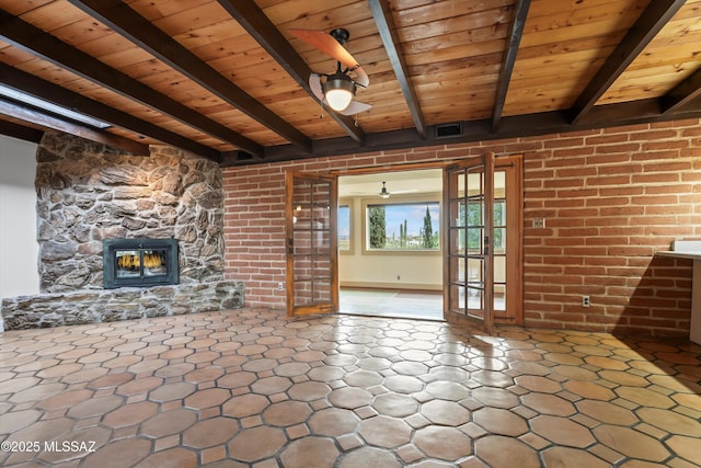 unfurnished living room featuring french doors, a fireplace, visible vents, wooden ceiling, and beamed ceiling