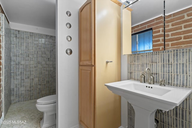 bathroom with backsplash, a sink, toilet, and tile walls