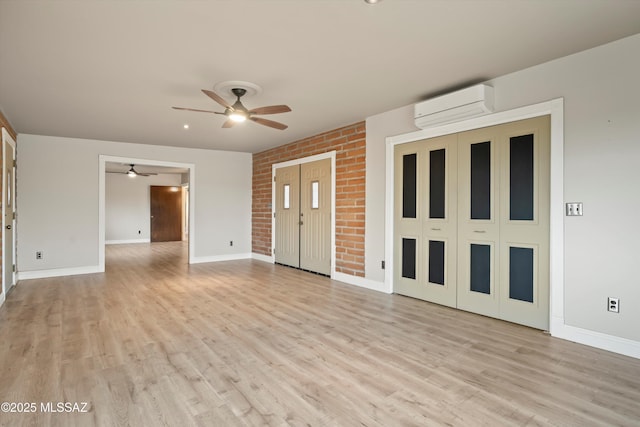 interior space with light wood-type flooring, a wall mounted air conditioner, and baseboards