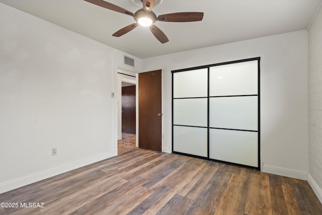 unfurnished bedroom featuring a ceiling fan, visible vents, baseboards, and wood finished floors