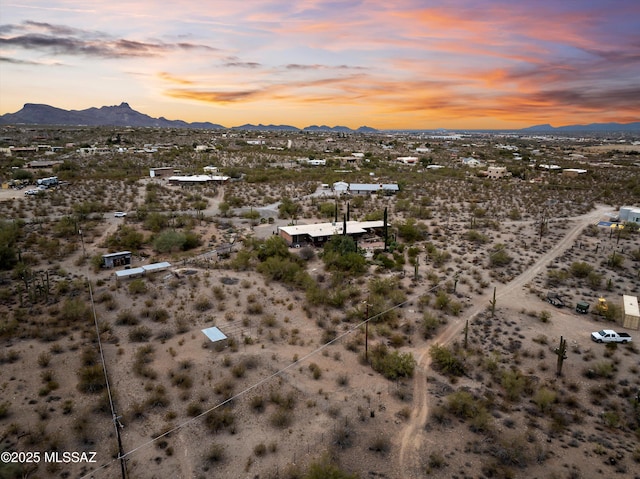 aerial view at dusk featuring a desert view and a mountain view